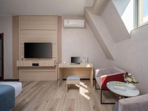 a living room with a bed and a desk with a television at Borrman Hotel Yuxi Yuxing Road in Yuxi