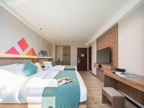 a bedroom with two beds and a flat screen tv at Borrman Hotel Yuxi Yuxing Road in Yuxi