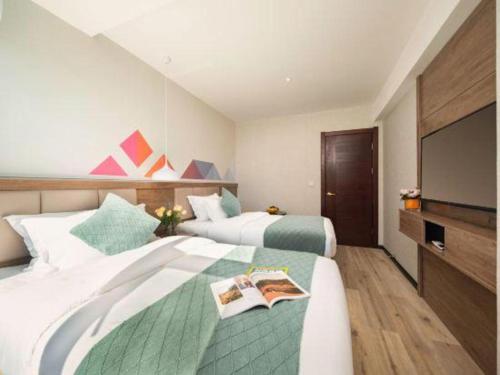 a hotel room with two beds and a flat screen tv at Borrman Hotel Yuxi Yuxing Road in Yuxi
