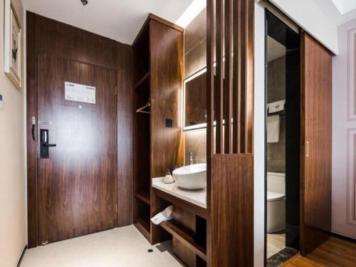 a bathroom with a sink and a wooden wall at GEM Hotel Changzhou Xuejia'aoyuan North High-Speed Railway Station in Changzhou