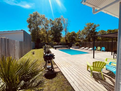 une arrière-cour avec une terrasse en bois et une piscine dans l'établissement Maison Papillon piscine couverte, à Grayan-et-lʼHôpital