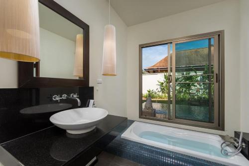 baño con lavabo y bañera con ventana en Villa Kaheru | 3 bedroom priavate pool villa | Kokyang Estate, en Nai Harn Beach