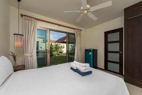 Un dormitorio con una cama grande con ventilador de techo. en Villa Kaheru | 3 bedroom priavate pool villa | Kokyang Estate, en Nai Harn Beach