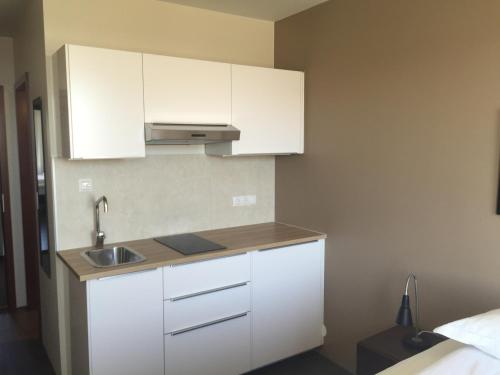 a kitchen with white cabinets and a sink at North Star Apartments Rif in Snæfellsbær
