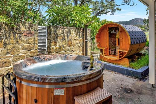 a hot tub in a wooden barrel next to a building at Brokenback Vineyard Homestead in Pokolbin