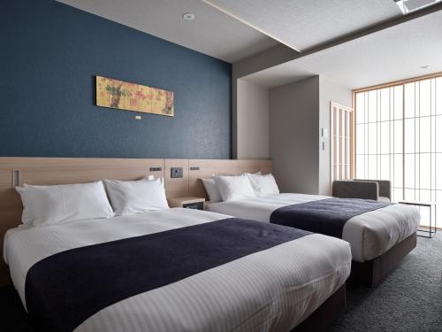 a hotel room with two beds in a room at Premium Apart MONday KYOTO GOJO in Kyoto