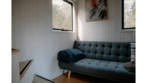 a living room with a blue couch and a window at Banyula Cove by Tiny Away in Barnes Bay