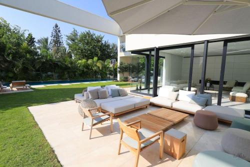 a patio with a couch and chairs and a table at Breathtaking Villa w Pool & Sauna Near the Beach by Sea N' Rent in Herzelia 