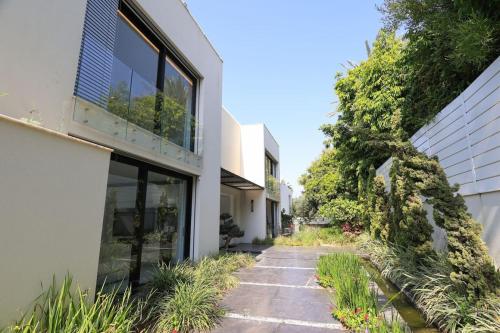 a walkway between two buildings with plants at Breathtaking Villa w Pool & Sauna Near the Beach by Sea N' Rent in Herzelia 