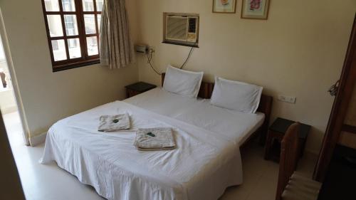 a bedroom with a bed with two towels on it at Candolim Beach Apartments Goa in Candolim
