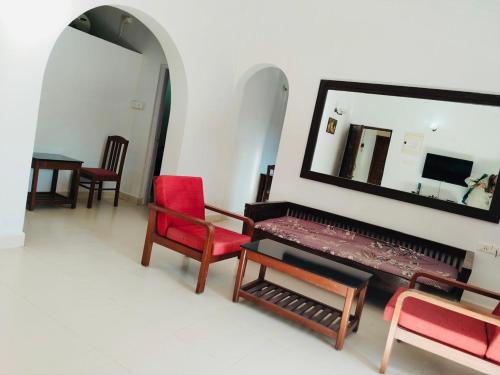a room with a piano and two chairs and a mirror at Candolim Beach Apartments Goa in Candolim