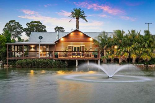 a house with a fountain in the middle of a pond at Lilies Lakeside Spa Villa - 2 Bedroom in Lovedale