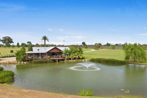 a house with a pond in front of it at Lilies Lakeside Spa Villa - 2 Bedroom in Lovedale