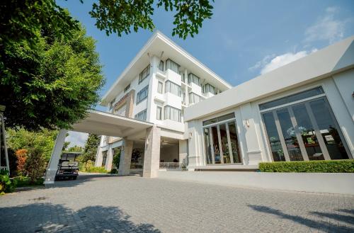 a white building with a car parked in front of it at THE NAVY HOUSE HOTEL in Sattahip