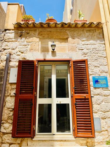 a window with wooden shutters on a stone building at RiccioDiMare in Donnalucata