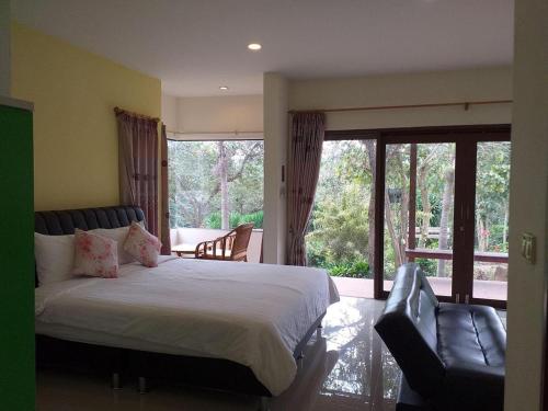 a bedroom with a bed and a couch and a balcony at Raisubsomboon Resort in Ban Don Wan