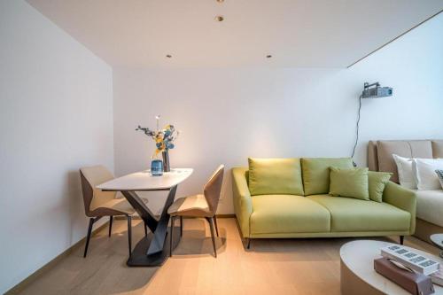 a living room with a green couch and a table at F-TOWN Fangtang Hotel (Shenzhen Longgang Tian'an Digital City Huanggekeng Subway Station) in Shenzhen
