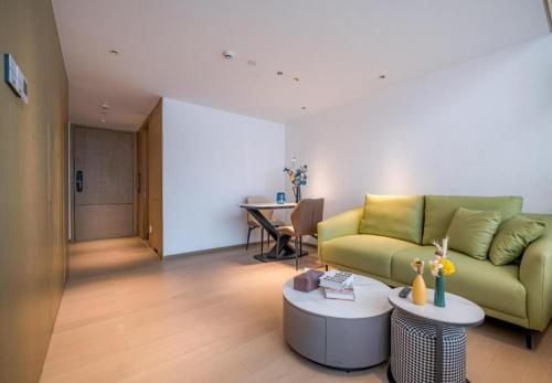 a living room with a green couch and a table at F-TOWN Fangtang Hotel (Shenzhen Longgang Tian'an Digital City Huanggekeng Subway Station) in Shenzhen