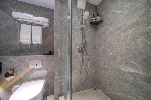 a bathroom with a shower with a toilet and a sink at F-TOWN Fangtang Hotel (Shenzhen Longgang Tian'an Digital City Huanggekeng Subway Station) in Shenzhen