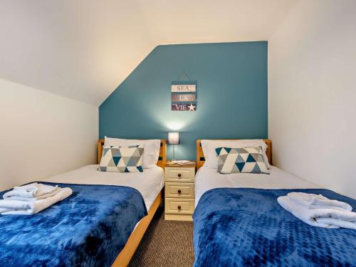two beds in a room with blue walls at 2 Bed in Filey 89281 in Hunmanby