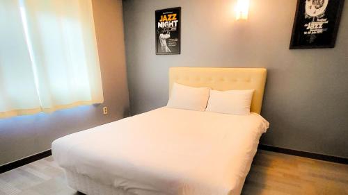 a bedroom with a white bed with two pillows at Jeju EQ Stay in Jeju