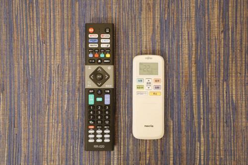 two remote controls sitting next to each other on a couch at blue sea and house in Nanjo