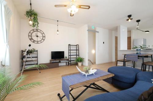 a living room with blue furniture and a clock on the wall at blue sea and house in Nanjo