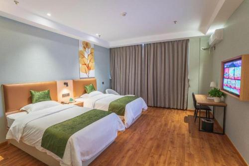 una camera d'albergo con due letti e una televisione di GreenTree Inn Express Suzhou Luzhi Ancient Town Scenic Area Xiaoshi Road a Suzhou