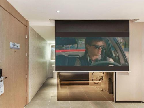 a tv with a man sitting in a car at Borrman Hotel Chongqing Bishan Central Street in Chongqing