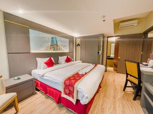 a hotel room with a large bed with red pillows at Hermes Palace Hotel Medan in Medan