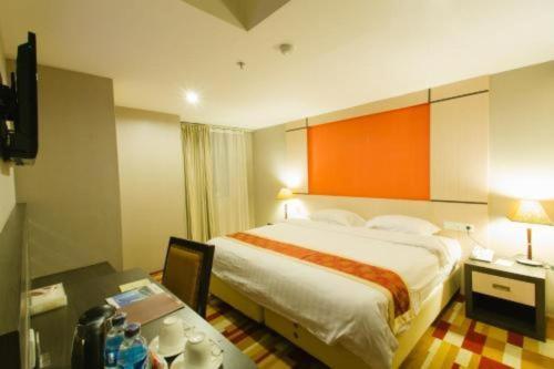 a hotel room with a large bed and a desk at Hermes Palace Hotel Medan in Medan