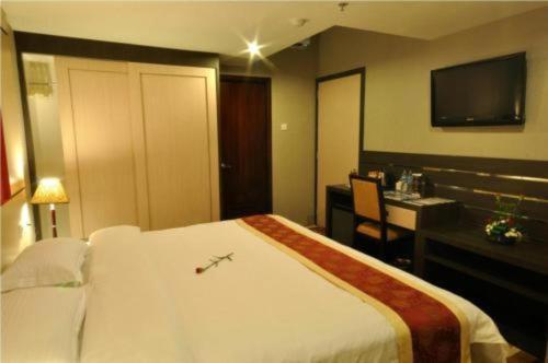 a hotel room with a bed and a desk and a television at Hermes Palace Hotel Medan in Medan