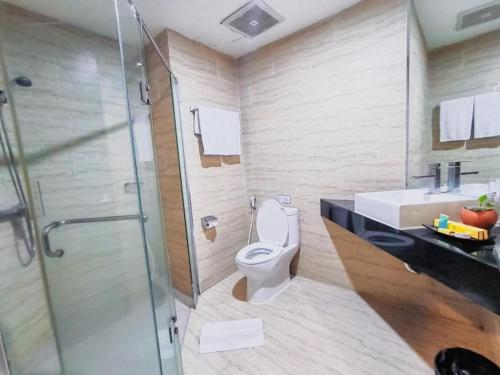 a bathroom with a toilet and a sink and a shower at Hermes Palace Hotel Medan in Medan
