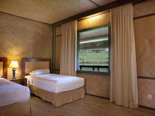 a hotel room with two beds and a window at Sambi Resort, Spa & Resto in Yogyakarta