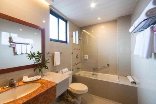 a bathroom with a sink and a toilet and a tub at Hotel Veniz in Baguio