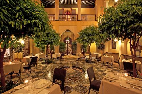 um restaurante com mesas brancas, cadeiras e árvores em Riyad Al Moussika em Marrakech