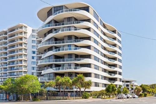 a tall apartment building with palm trees in front of it at Breeze Mooloolaba (APT 503) in Mooloolaba