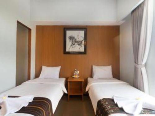 a room with two beds and a table at Hadi Poetra Hotel in Kuta