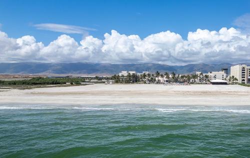a beach with buildings in the background and the ocean at Hilton Salalah Resort in Salalah