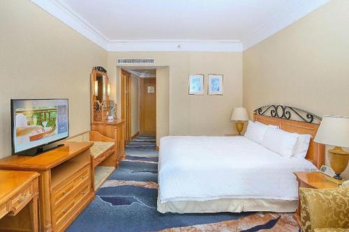 a hotel room with a bed and a television at Regency Hotel in Shantou