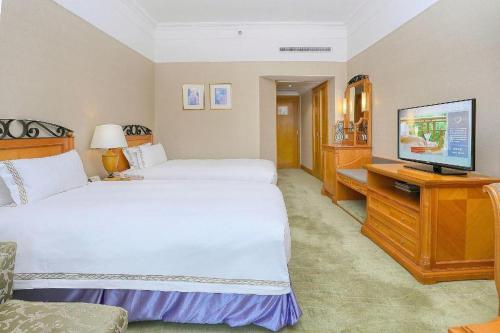 a hotel room with two beds and a flat screen tv at Regency Hotel in Shantou