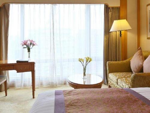 a hotel room with a bed and a couch and a table at Regency Hotel in Shantou