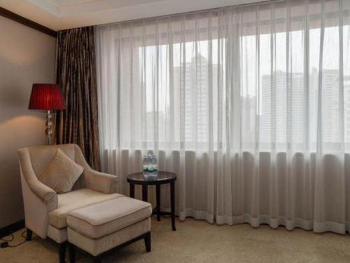 a living room with a chair and a window at SUN Yat-sen university Hotel and Conference Centre in Guangzhou