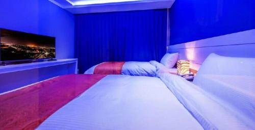 a bedroom with a large bed with a tv on the wall at Galaxy Hotel in Jeju