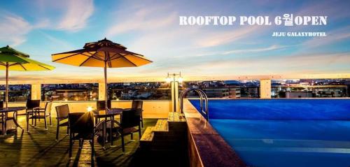 a rooftop pool with tables and umbrellas on a building at Galaxy Hotel in Jeju