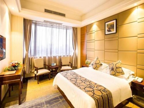 a hotel room with a bed and a table and chairs at GreenTree Inn GuangDong JieYang Bus Terminal Station RongHua Avenue Business Hotel in Jieyang