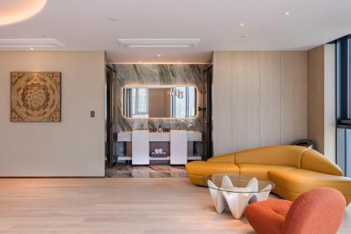 a living room with a yellow couch and a sink at Jeju Bolton Hotel in Jeju