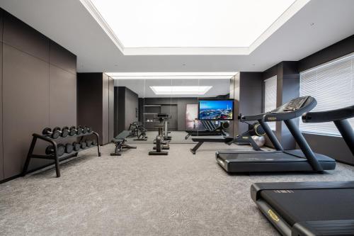 a gym with several tread machines and a flat screen tv at Taiyuan Jinyang Lake Intercity Hotel in Taiyuan
