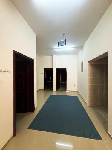 an empty room with a blue rug on the floor at Maison Masirah in Ḩilf