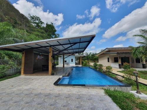 a swimming pool in front of a house at Phuphayot Resort in Huai Yot
